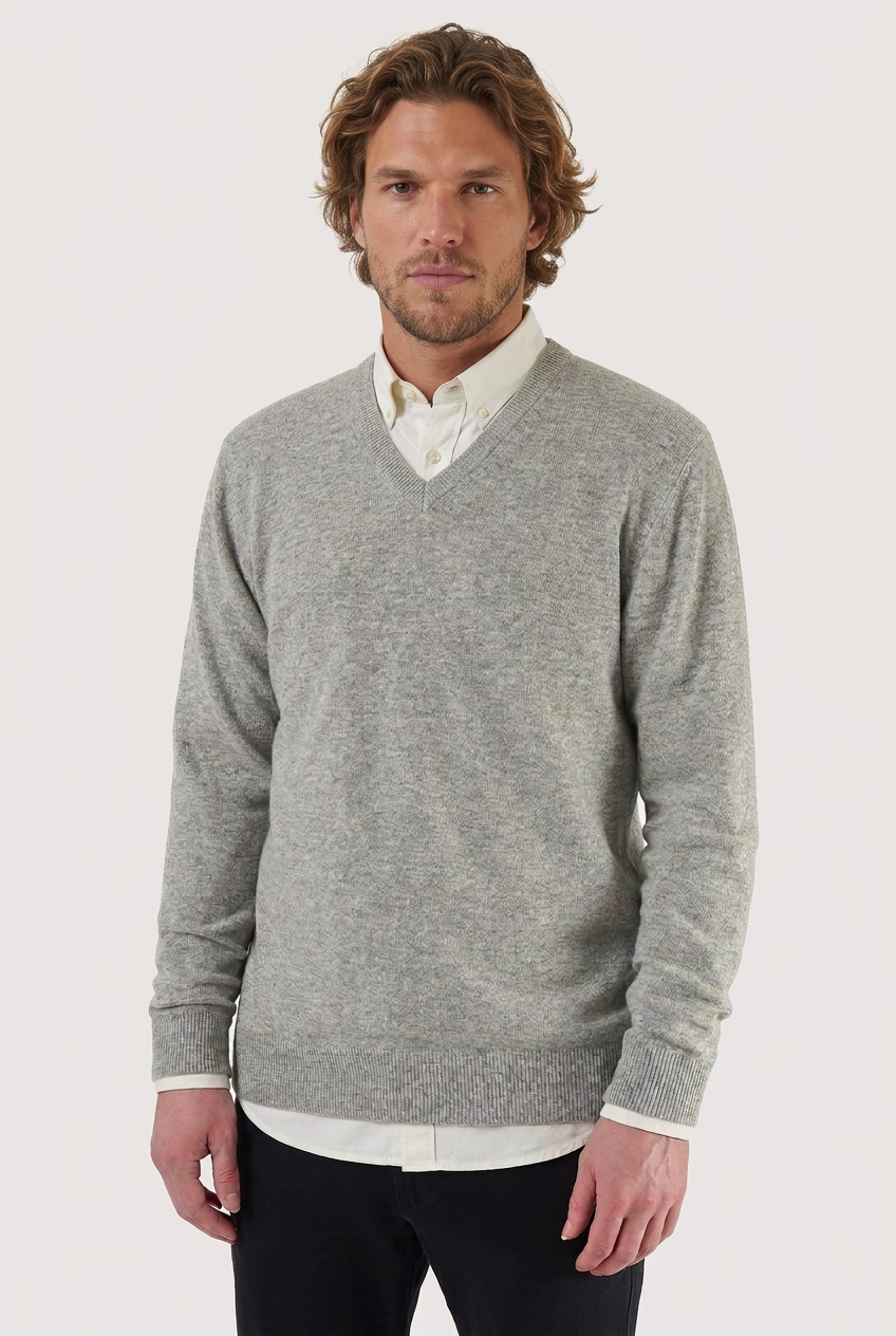 Camisola de lã cinzenta com decote em V vestida por modelo com camisa branca