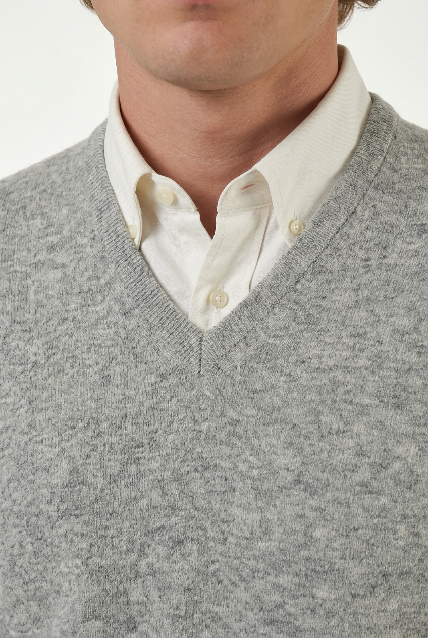 Detalhe da malha e do decote em V da camisola cinzenta com camisa branca