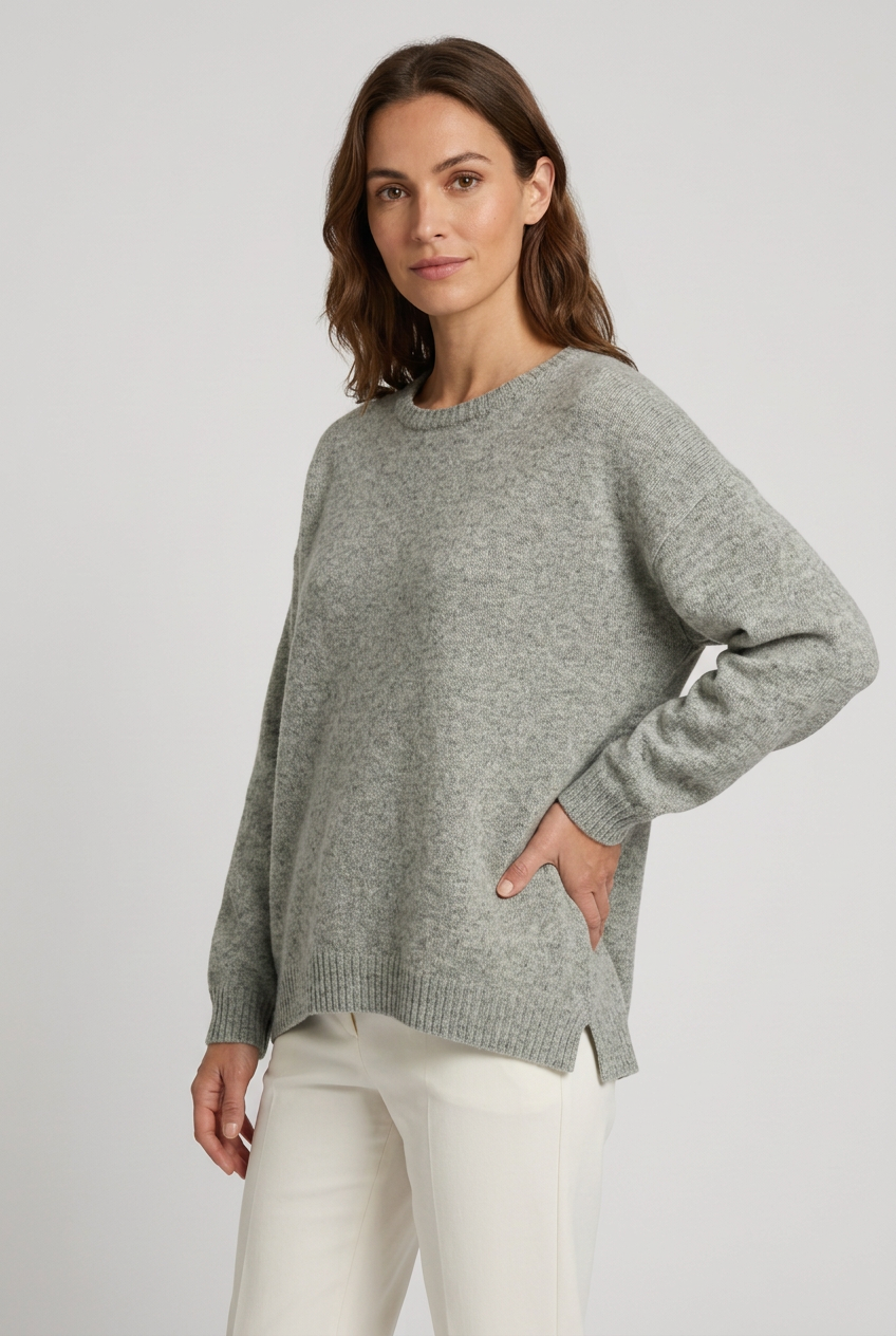 Camisola de lã oversized cinzenta vestida por modelo em pose de três quartos com uma mão na anca